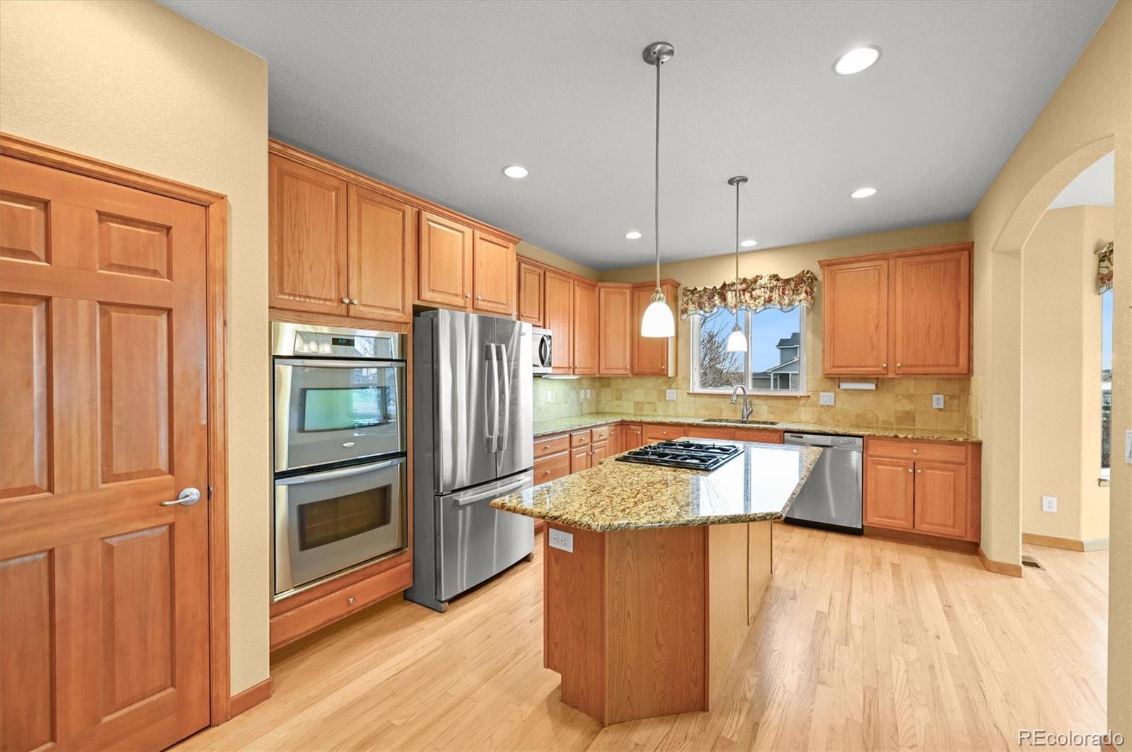 16231 Rayburn Street Hudson, CO 80642 - Photo 14 of 50 a kitchen with stainless steel appliances granite countertop a refrigerator a sink dishwasher a oven with wooden cabinets and floor