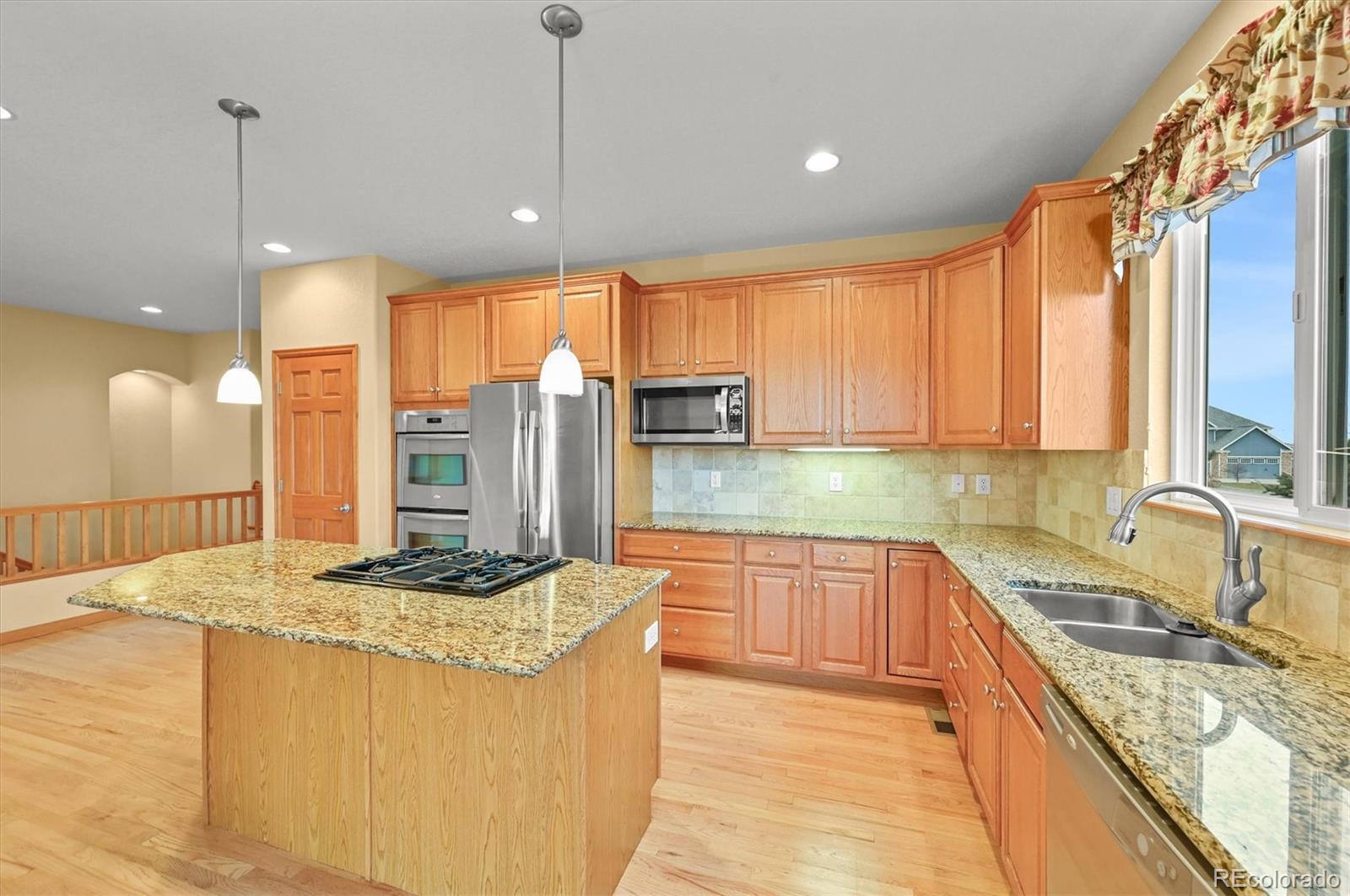 16231 Rayburn Street Hudson, CO 80642 - Photo 15 of 50 a kitchen with stainless steel appliances granite countertop a sink stove and refrigerator