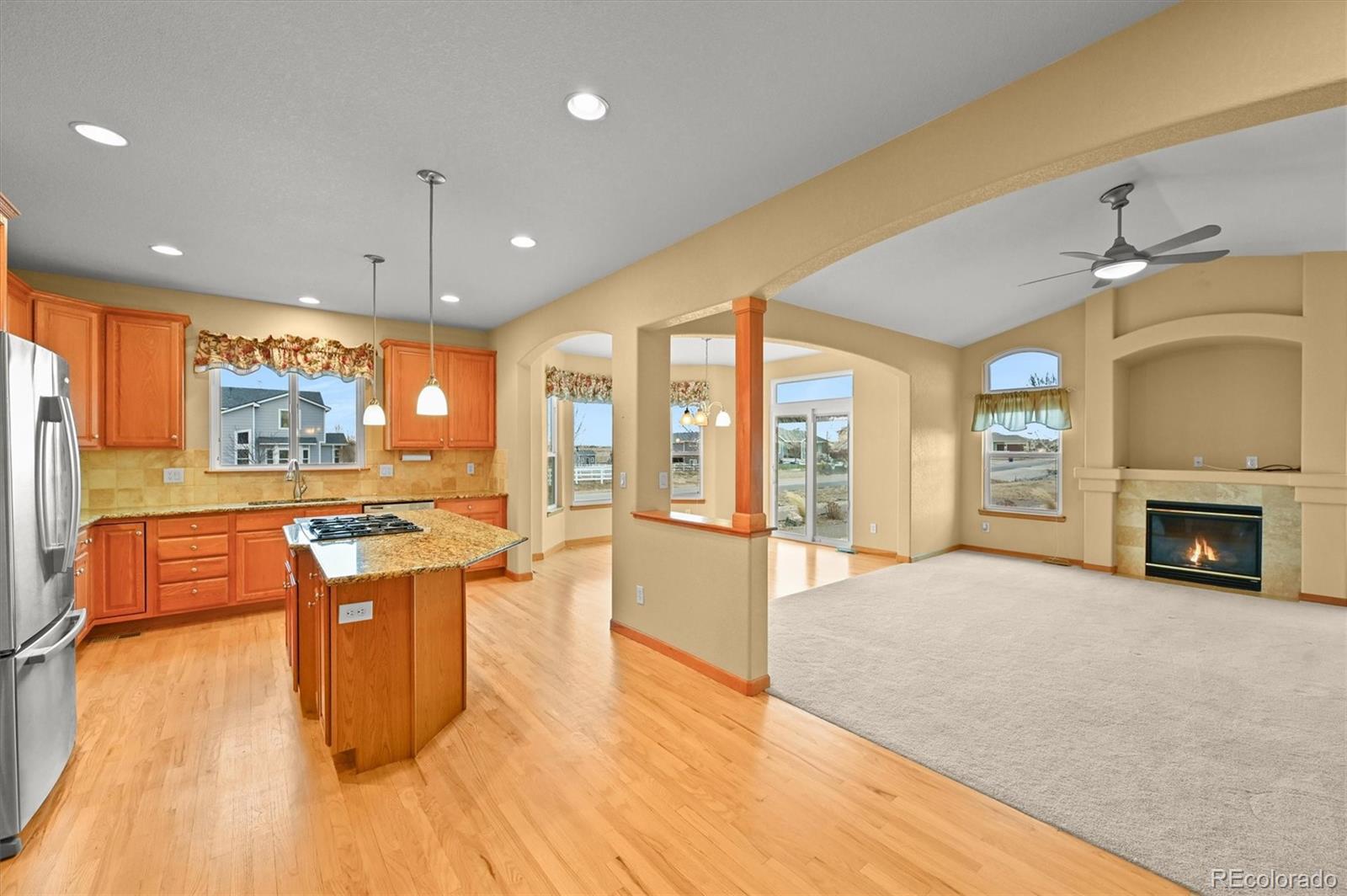 16231 Rayburn Street Hudson, CO 80642 - Photo 17 of 50 a large kitchen with stainless steel appliances granite countertop a refrigerator a oven a dining table and chairs with wooden floor