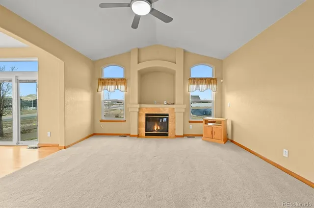 a view of a livingroom with a fireplace a ceiling fan and windows