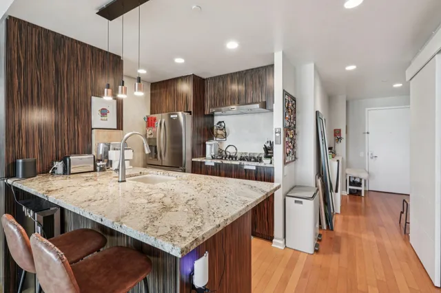a kitchen with stainless steel appliances kitchen island granite countertop wooden floor and refrigerator