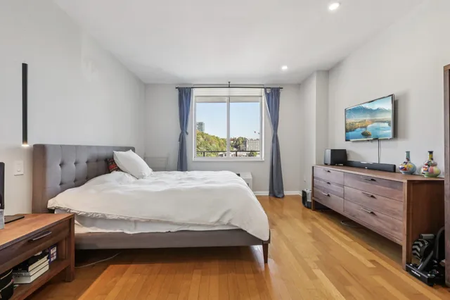 a bedroom with a bed and a flat tv screen on dresser