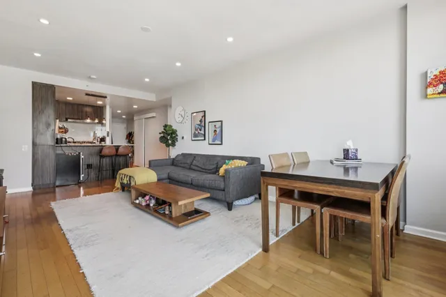 a living room with furniture and a dining table with wooden floor