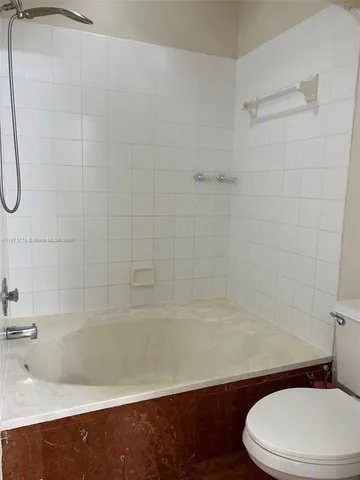 a white toilet sitting next to a bath tub