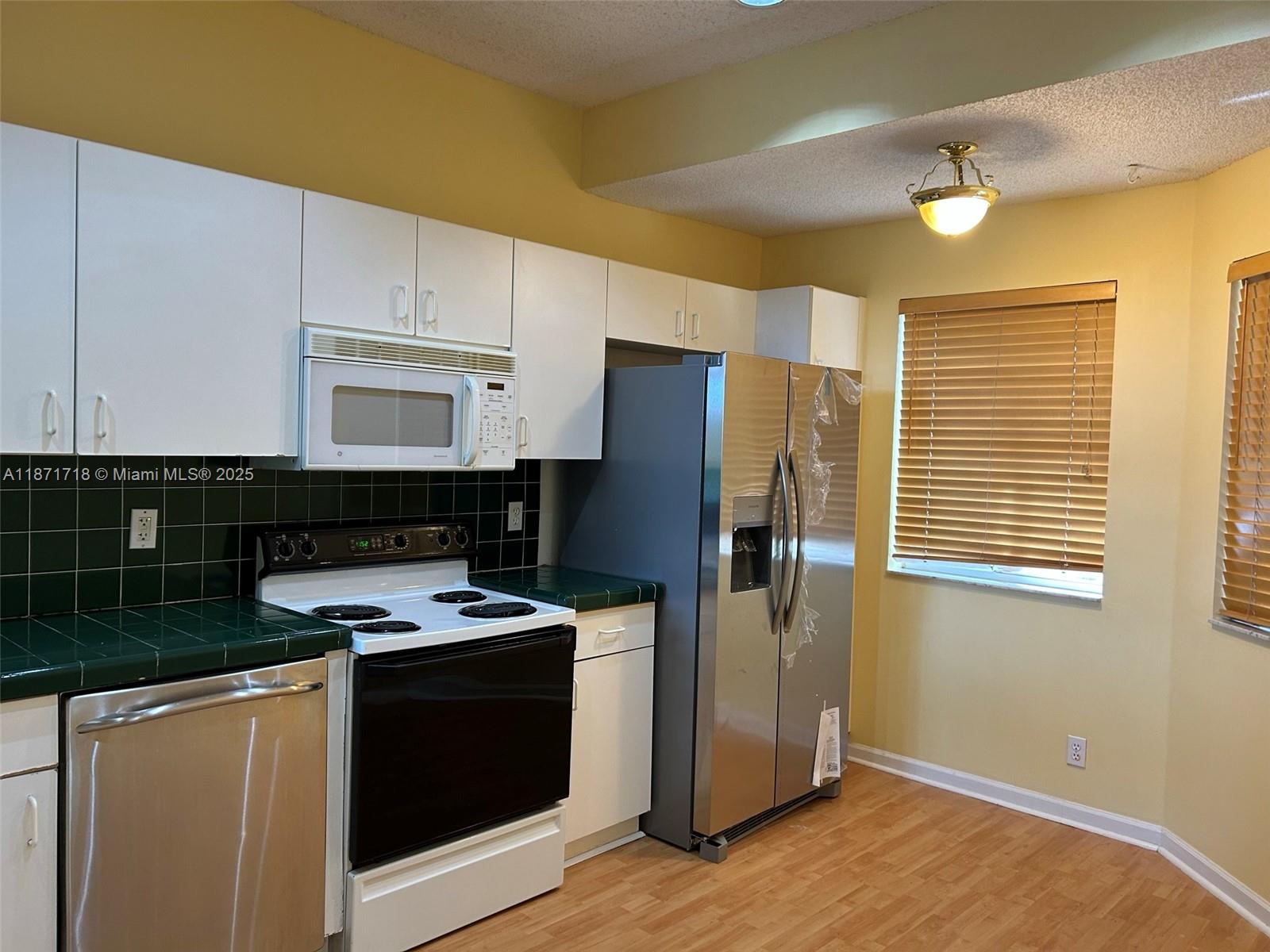 15851 Southwest 10th Street, Unit 15851 Pembroke Pines, FL 33027 - Photo 5 of 17 a kitchen with stainless steel appliances granite countertop a stove a refrigerator and a microwave
