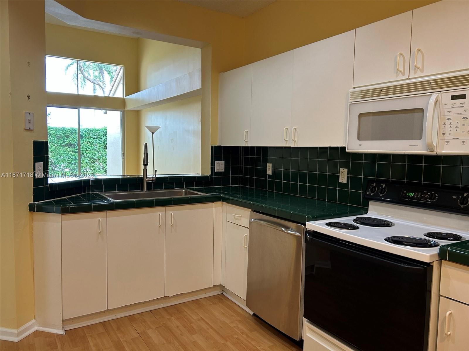 15851 Southwest 10th Street, Unit 15851 Pembroke Pines, FL 33027 - Photo 6 of 17 a kitchen with granite countertop a stove a sink and a microwave