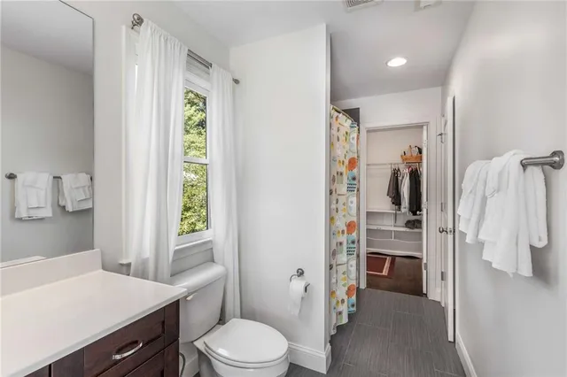 a bathroom with a sink a toilet a window and shower