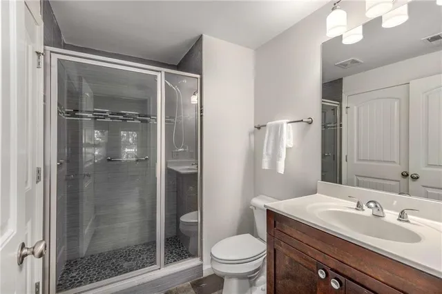 a bathroom with a shower sink vanity mirror and toilet