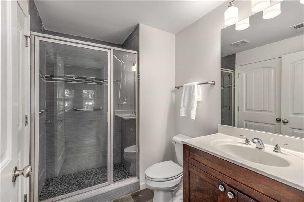 2456 Sunset Drive Northeast Atlanta, GA 30345 - Photo 40 of 49 a bathroom with a shower sink vanity mirror and toilet