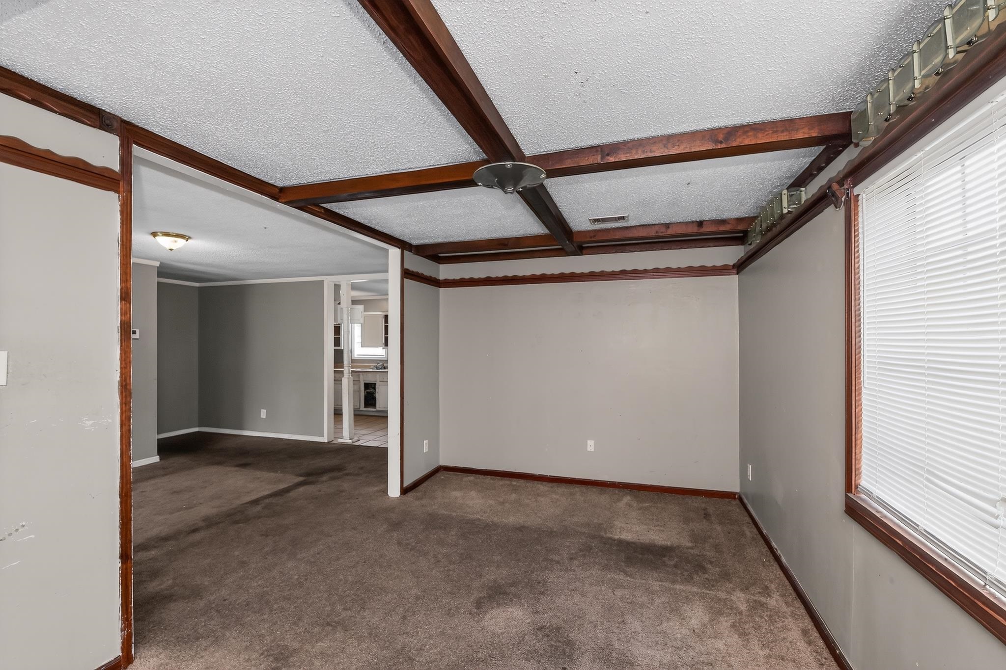 3791 Windermere Road Memphis, TN 38128 - Photo 5 of 18 Spacious interior room featuring textured ceilings with exposed faux wood beams, a large window with blinds, and neutral-toned wall paint