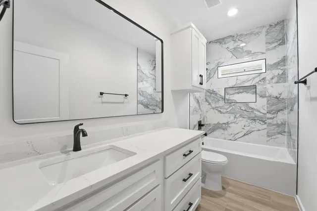 a bathroom with a sink a toilet a vanity and bathtub