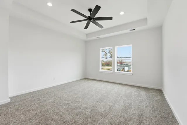 an empty room with windows and fan