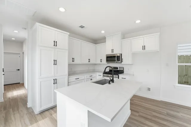 a kitchen with a refrigerator a stove top oven a sink and cabinets