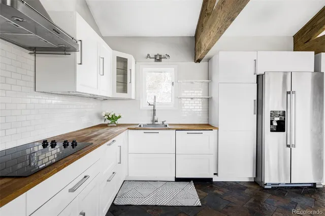 a kitchen with granite countertop a white refrigerator oven a sink and white cabinets with wooden floor