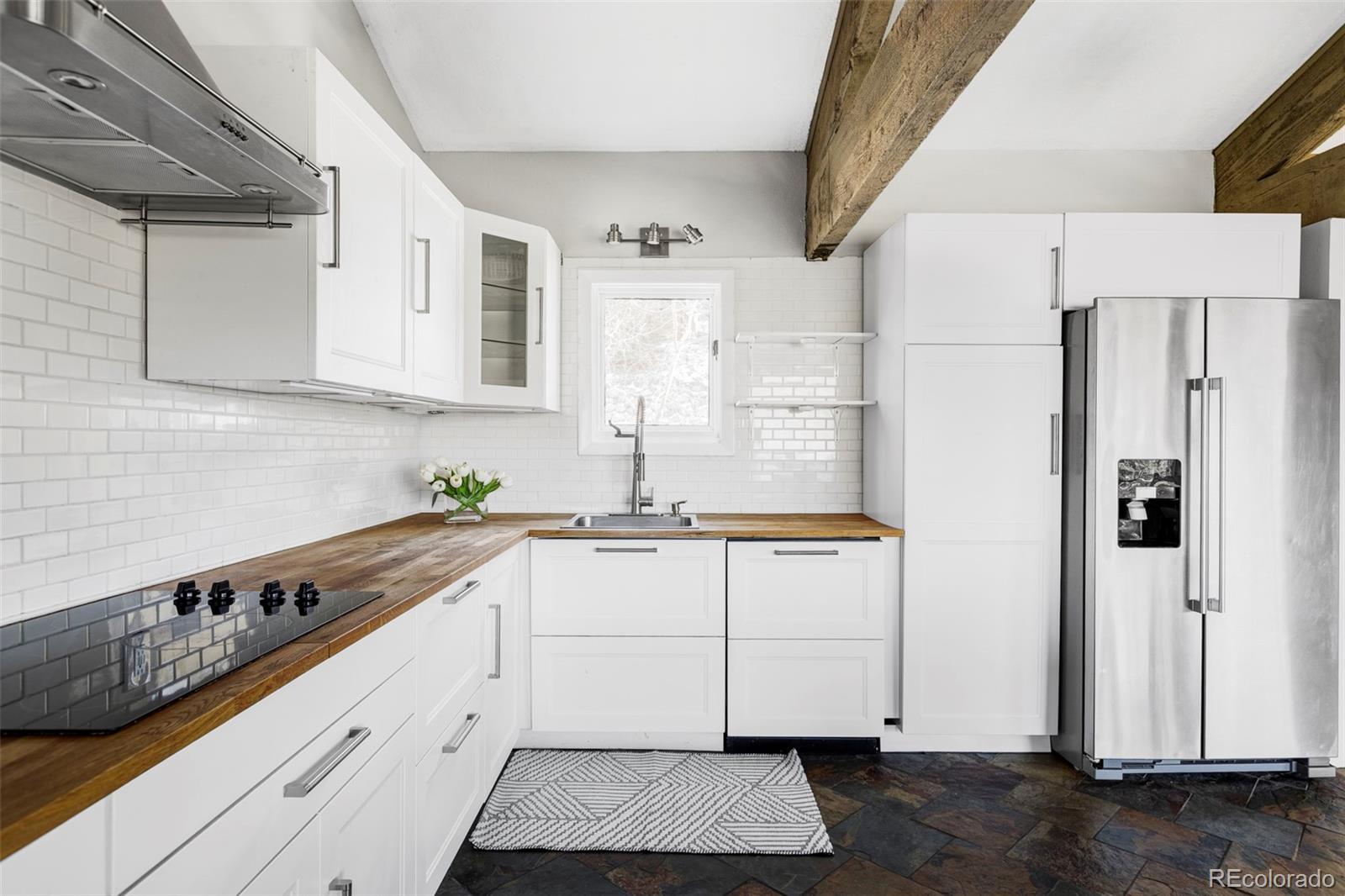 297 Deer Path Road Dillon, CO 80435 - Photo 9 of 49 a kitchen with granite countertop a white refrigerator oven a sink and white cabinets with wooden floor