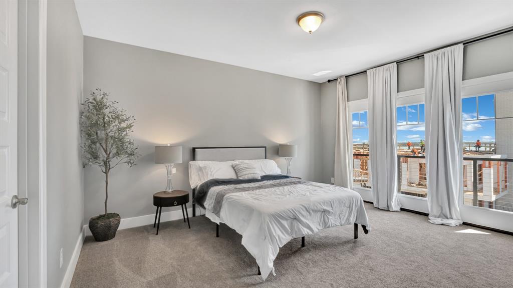 602 Winners Circle Rowlett, TX 75088 - Photo 22 of 35 Third level, secondary bedroom, carpeted, featuring an ensuite, light gray color palette, multiple large windows with white trim, and a ceiling-mounted light fixture