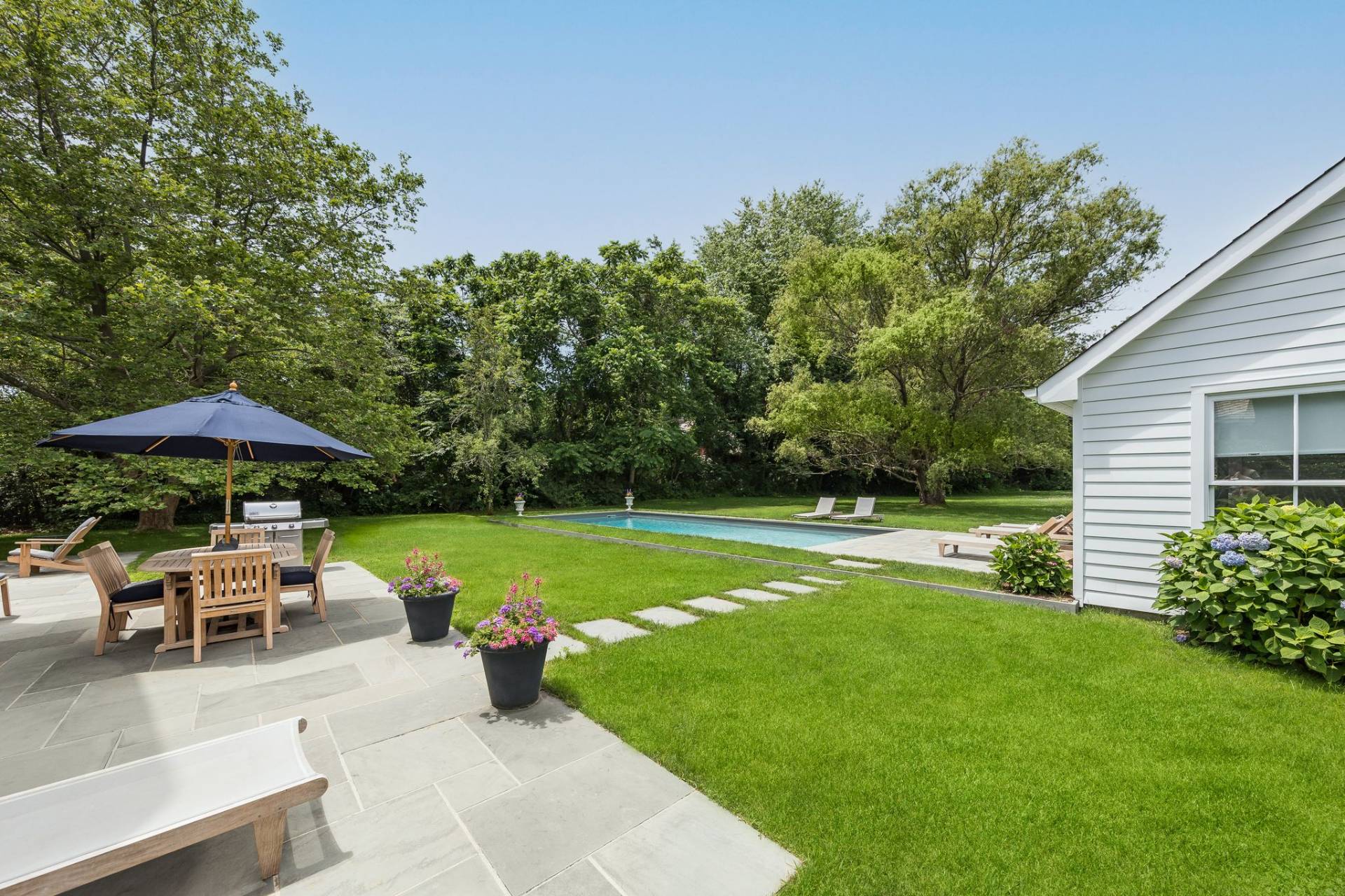 124 Ocean Road Bridgehampton, NY 11932 - Photo 7 of 27 a view of a swimming pool and lounge chairs in back yard of the house