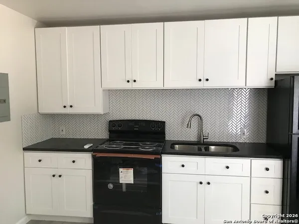 a kitchen with white cabinets and black appliances