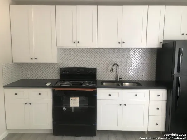 a kitchen with granite countertop white cabinets and stainless steel appliances