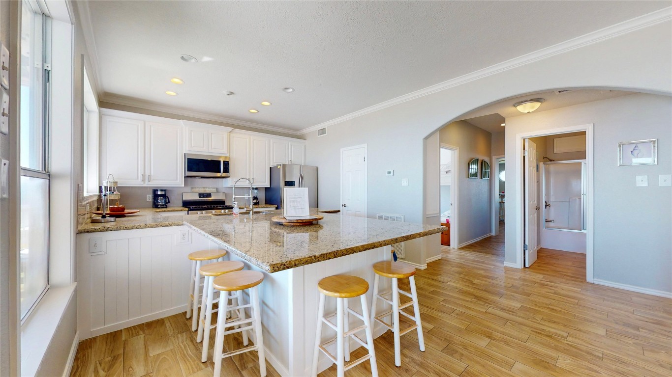 3433 Sand Castle Lane Crystal Beach, TX 77650 - Photo 23 of 30 a kitchen with stainless steel appliances a dining table chairs and wooden floor