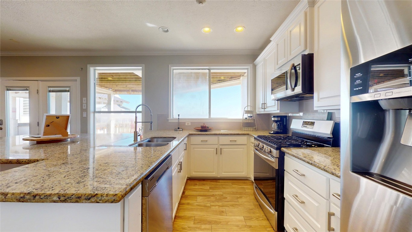 3433 Sand Castle Lane Crystal Beach, TX 77650 - Photo 25 of 30 a kitchen with stainless steel appliances granite countertop a sink stove and refrigerator