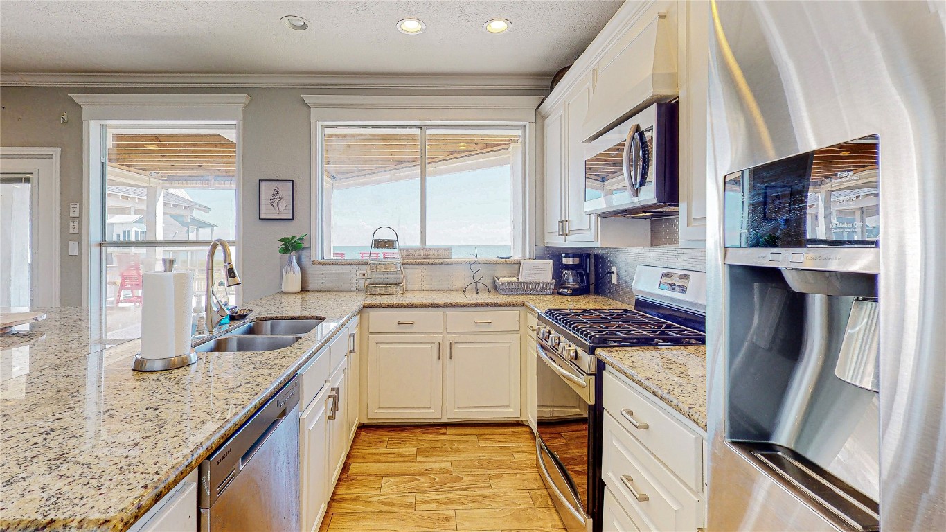 3433 Sand Castle Lane Crystal Beach, TX 77650 - Photo 6 of 30 a kitchen with stainless steel appliances granite countertop sink stove refrigerator and cabinets