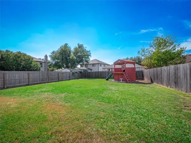 a view of a backyard with large trees and wooden fence