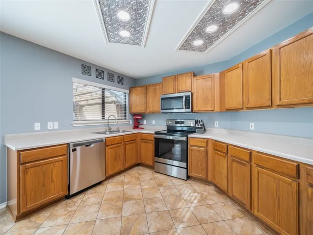 a kitchen with stainless steel appliances granite countertop a stove sink microwave and window