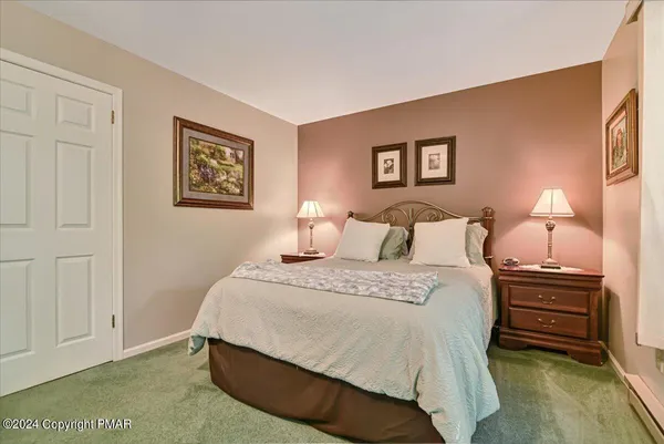 a spacious bedroom with a bed and a lamp on dresser