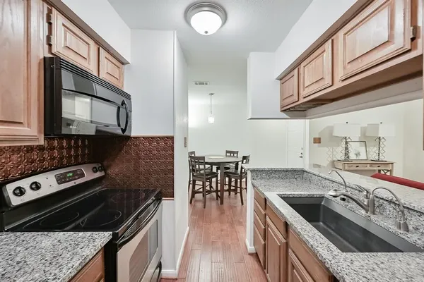 a kitchen with stainless steel appliances granite countertop a stove a sink dishwasher and cabinets with wooden floor