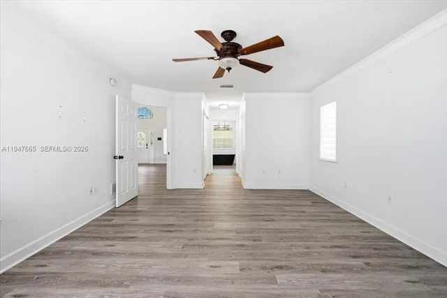 a view of an empty room with window and wooden floor