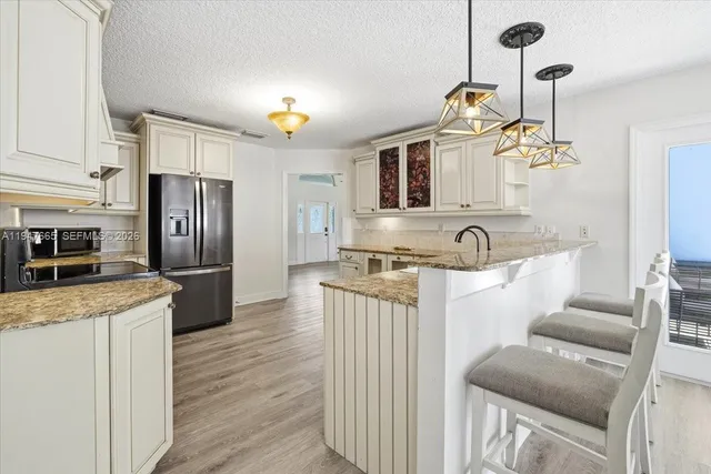 a kitchen with stainless steel appliances granite countertop a refrigerator a stove and a sink