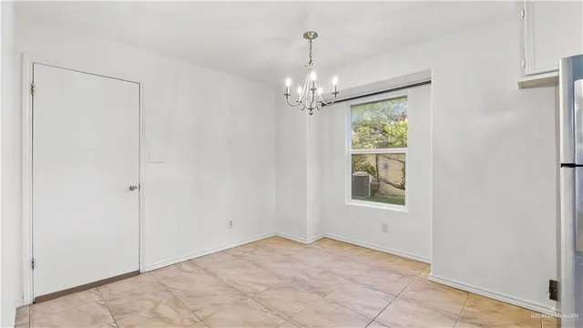 a view of an empty room with window and chandelier