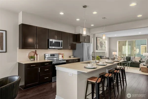 a kitchen with stainless steel appliances kitchen island granite countertop a stove a sink a dining table and chairs