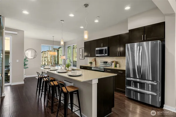 a kitchen with stainless steel appliances a table chairs microwave and refrigerator