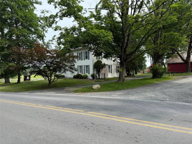 a view of a house with a big yard and large trees