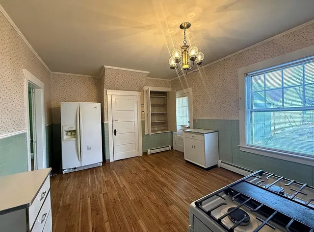 an empty room with wooden floor cabinet and windows