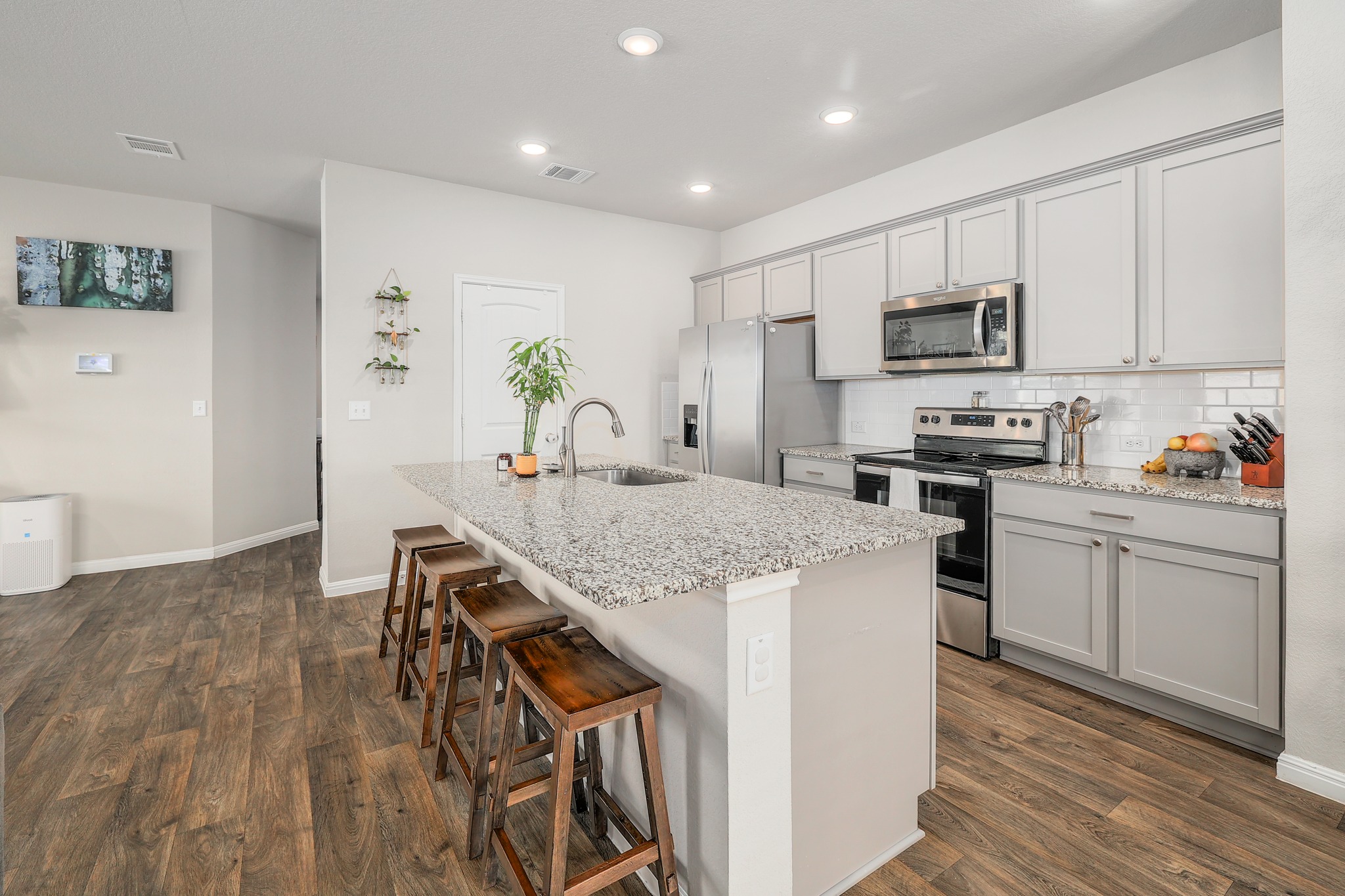 413 Hunter Loop Bertram, TX 78605 - Photo 10 of 27 Bright contemporary kitchen featuring shaker-style cabinetry, stainless steel appliances, granite countertops, recessed lighting, and a large island with breakfast bar seating.