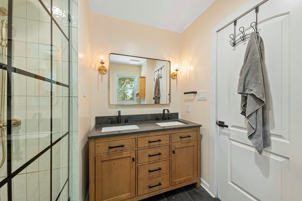 7047 Mellwood Road Columbus, GA 31904 - Photo 20 of 34 a bathroom with a granite countertop sink a mirror a vanity and shower