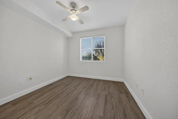 an empty room with a window and a ceiling fan
