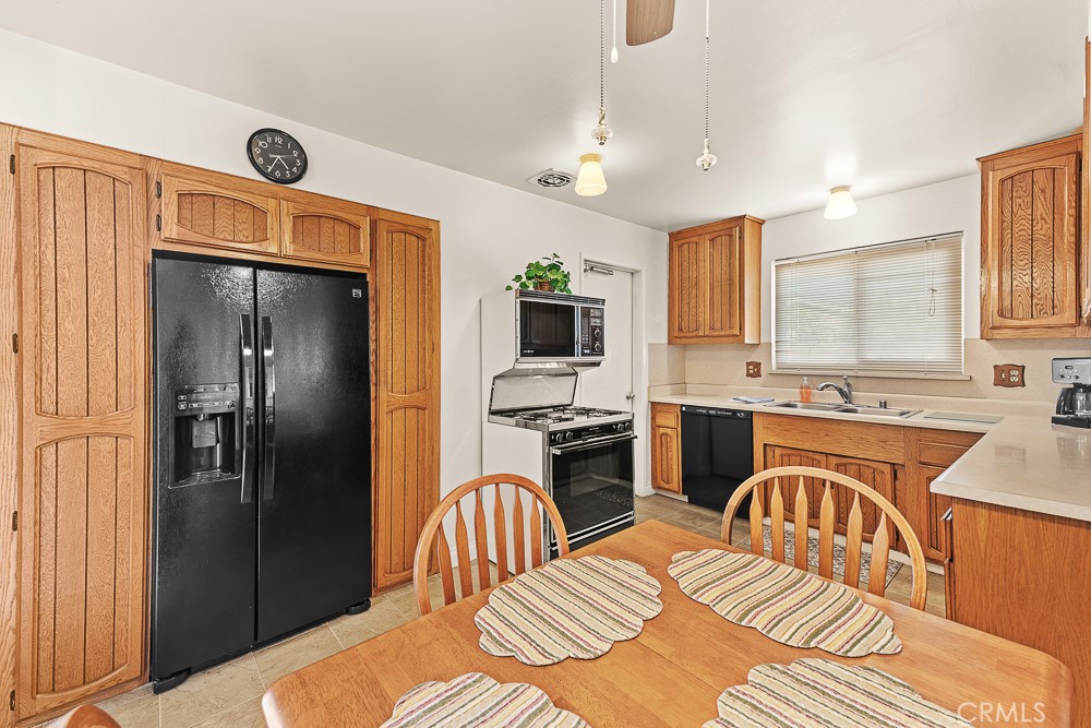 10282 Longden Street Cypress, CA 90630 - Photo 25 of 43 a kitchen with stainless steel appliances granite countertop a refrigerator a stove a sink dishwasher a dining table and chairs with wooden floor