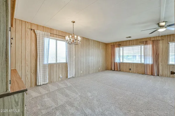 en empty room with windows and chandelier fan