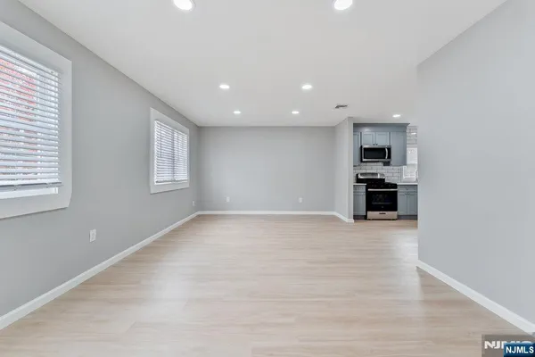 a view of empty room with kitchen and window