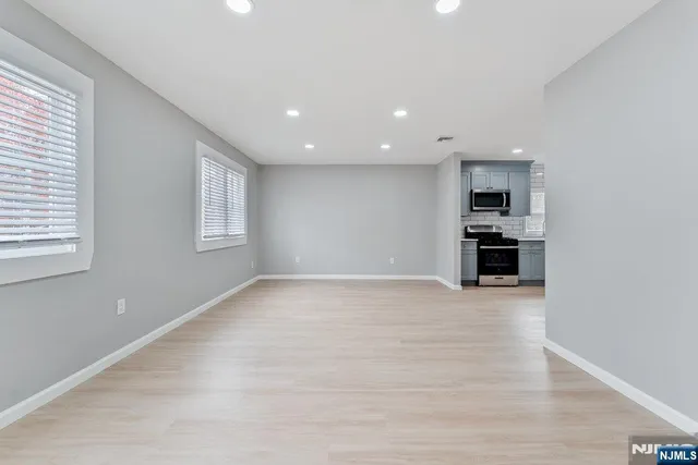 a view of empty room with kitchen and window