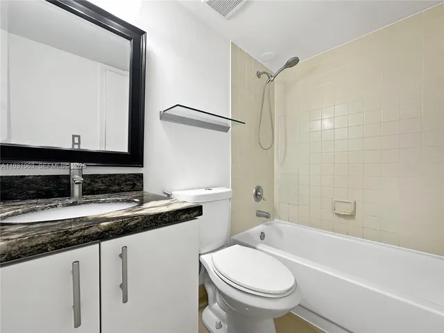 a bathroom with a granite countertop sink toilet mirror and bathtub