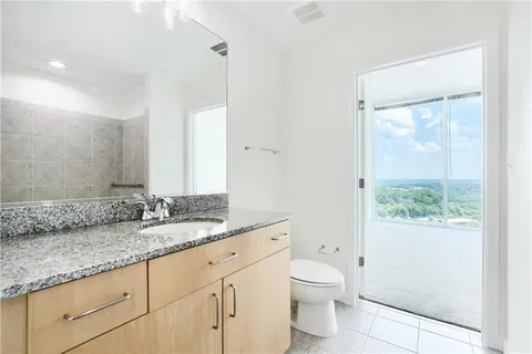 a bathroom with a granite countertop sink a toilet and a mirror