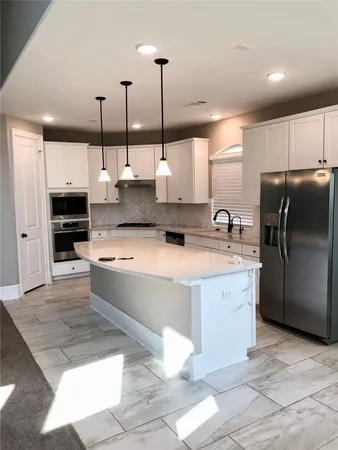 a large kitchen with stainless steel appliances kitchen island granite countertop a refrigerator a sink and a stove