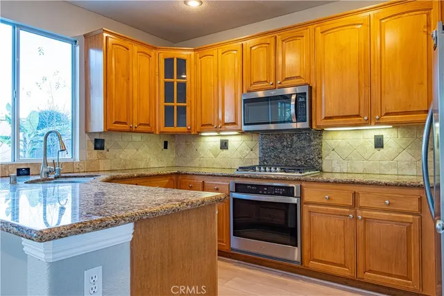 a kitchen with granite countertop wooden cabinets a sink and a stove next to a window