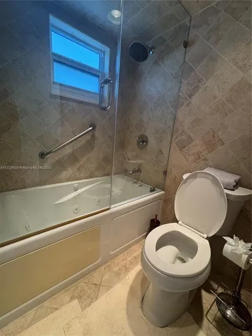 a white toilet sitting next to a bath tub and shower