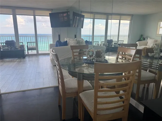 a dining room with furniture large windows and wooden floor